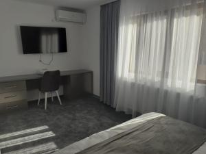 Dormitorio con cama, escritorio y TV en Motel Moara Veche en Săcălăşeni
