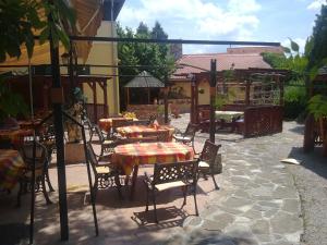 eine Terrasse mit Tischen und Stühlen sowie einem Tisch und Stühlen in der Unterkunft Vadász Panzió és Étterem in Szombathely