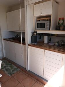 a kitchen with white cabinets and a microwave at Appartement Bilimbi Guadeloupe entre Sainte-Anne et Saint-François in Sainte-Anne