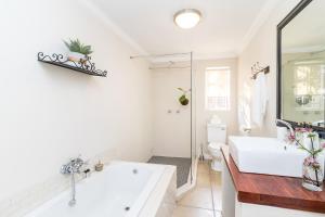un bagno bianco con vasca e lavandino di Jeppe house cottage a Pretoria