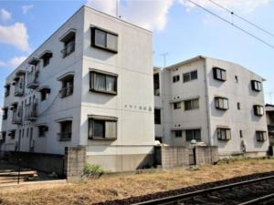 un edificio blanco con ventanas junto a las vías del tren en Maison Ota Building A Building B - Vacation STAY 14501 en Takamatsu