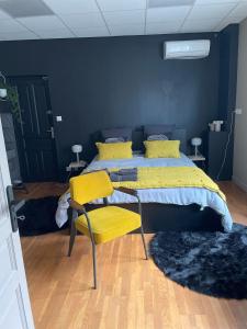um quarto com uma cama com lençóis amarelos e cadeiras amarelas em Chambre marais em Écourt-Saint-Quentin