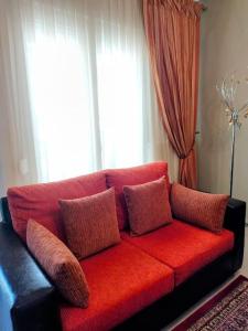 un sofá rojo con almohadas en la sala de estar en Evaggelia's Apartments 5 Οικογενειακό Διαμέρισμα, en Kozani