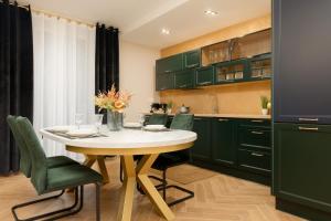 a kitchen with green cabinets and a white table and chairs at Ursus Nova Apartment with Parking by Renters Prestige in Warszawa