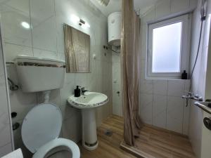 een badkamer met een toilet, een wastafel en een douche bij Community Park Apartment in Niš