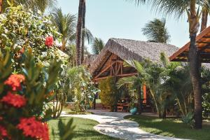 a resort with a pathway and palm trees and flowers at Pousada Meeting Point & KiteSchool in Cumbuco