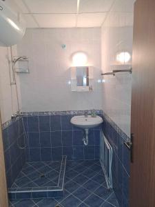 Un baño con azulejos azules, lavabo y espejo. en АПАРТАМЕНТ Амира 2, en Balchik 16 fotos más