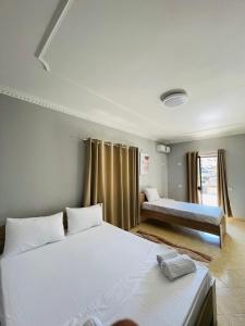 1 Schlafzimmer mit 2 Betten und einem Fenster mit Vorhängen in der Unterkunft Hotel Villa Ferrari in Tirana