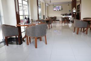 un comedor con mesas y sillas en un suelo de baldosas blancas en Paraiso Gardens Hotel en Wote
