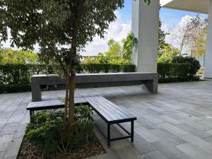 サイバージャヤにあるKyra Homestay Centrus SOHO Cyberjaya *wifi and pool*の中庭の木の横に座るベンチ