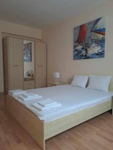 Un dormitorio con una gran cama blanca con un cuadro en la pared. en Апартамент "Амира", en Balchik