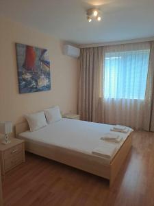 a bedroom with a large bed and a window at Апартамент "Амира" in Balchik