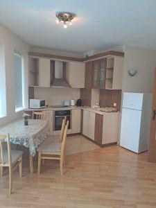 eine Küche mit einem Tisch und Stühlen sowie einem weißen Kühlschrank in der Unterkunft Апартамент "Амира" in Baltschik