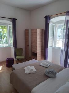 a bedroom with two beds and a chair and windows at Studio Apartman Ivanka in Orebić