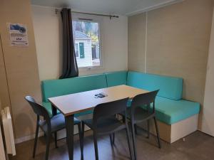 een eetkamer met een tafel en een groene bank bij Mobilhome 6 à 8 personnes camping 4 etoiles in Saint-Cyprien