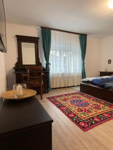 um quarto com uma cama, uma mesa e um tapete em Casa Popa em Valiug