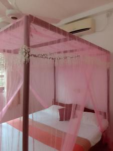 1 dormitorio con cama rosa y dosel en House of Rose, en Dodanduwa