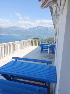 two blue benches sitting on a balcony overlooking the water at Apartments Vidikovac in Tivat