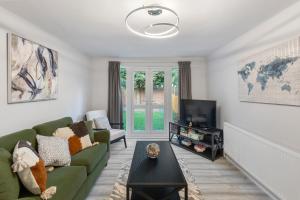 a living room with a green couch and a tv at Stunning 2 Bedroom House with Garden BBQ - Hampstead Heath Park in London