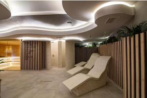 a lobby with white chairs and a ceiling at Theos apartman Titova vila in Zlatibor