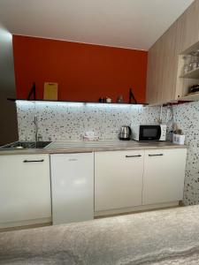 uma cozinha com armários brancos e uma parede vermelha em Квартира Тропики центр міста st Remisnycha 55a em Chernigov