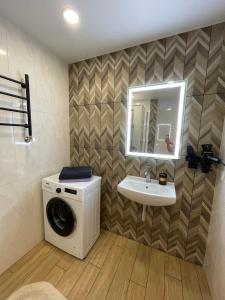 a bathroom with a washing machine and a sink at Квартира Тропики центр міста st Remisnycha 55a in Chernihiv