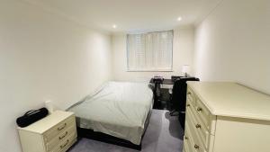 Schlafzimmer mit einem Bett, einem Schreibtisch und einem Fenster in der Unterkunft Enchantia Stayz: Central London's Exquisite Abodes in London