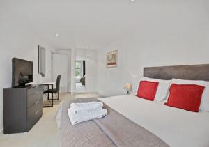 sypialnia z dużym łóżkiem z czerwonymi poduszkami i telewizorem w obiekcie Cubo Farringdon w Londynie