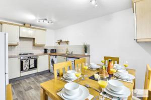 eine Küche mit einem Holztisch mit Tellern und Weingläsern in der Unterkunft Modern 4-Bedroom Gem Family & Business Friendly in Coalville