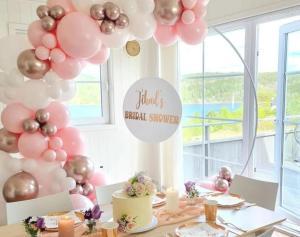 a table with pink and silver balloons and a cake at Lovely home by Glomma river! in Vidnes