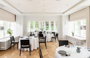 a restaurant with white tables and chairs and windows at Wasa Historical 1938 Boutique Hotel in Pärnu