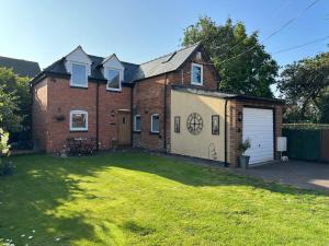 a brick house with a garage and a yard at Beautiful Coach House in Gloucester