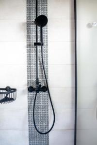 La salle de bains est pourvue d'une douche avec un pommeau de douche noir. dans l'établissement Gîte Le Carpe diem Milly-la-Forêt, à Milly-la-Forêt