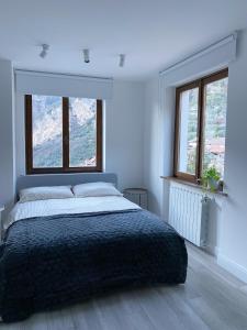 a white bedroom with a bed and two windows at Garda View Apartment in Tenno