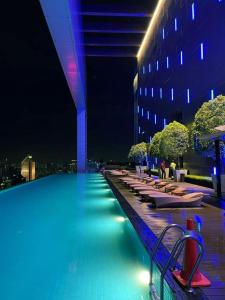 a swimming pool with chairs and a building at night at KLCC Sky Villa Suites Platinum in Kuala Lumpur