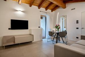 een woonkamer met een tv en een tafel met stoelen bij Appartamento Midum Domus Attic in Trento