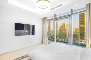 a white bedroom with a bed and a large window at Paramount Hotel Apartment Midtown - Platinium Dubai in Dubai