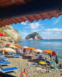 - une plage avec des chaises et des parasols et l'océan dans l'établissement BeachFront House - Sant'Angelo Ischia, à Ischia