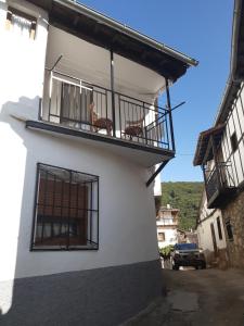 un edificio blanco con un balcón con sillas. en Casa de tía Patricia en Montemayor del Río