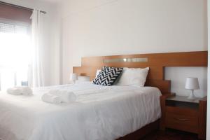 a bedroom with a large white bed with towels on it at GG Massamá Rooms in Queluz