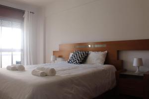 a bedroom with a large white bed with towels on it at GG Massamá Rooms in Queluz