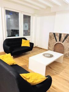 a living room with a black couch and yellow pillows at Superbe appartement aéroport et gare Charleroi in Charleroi