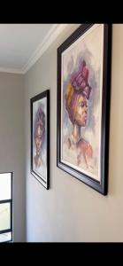 two paintings of a woman with a hat on a wall at Eagle of Kawele 3-bedroom villa in Sandton