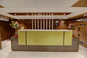 a lobby with a yellow counter and some flowers at Hotel The Furat Inn in Vapi