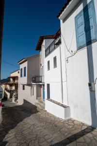 ein weißes Haus mit Balkon in einer Kopfsteinpflasterstraße in der Unterkunft Billy's Stonehouse in Samos