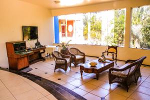 ein Wohnzimmer mit Stühlen, einem Tisch und einem TV in der Unterkunft Pasargada Hotel in Crato