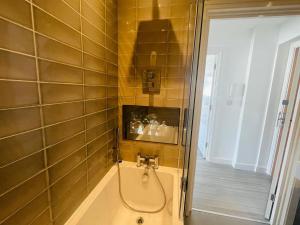 La salle de bains est pourvue d'une douche et d'une baignoire avec un tuyau. dans l'établissement Leigh On Sea - Prime Location! Ultra Modern Entire Apartment With Free Gated Parking & Private Balcony, à Southend-on-Sea