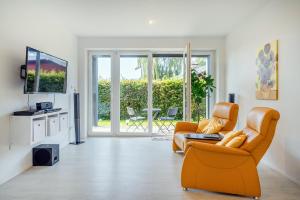 sala de estar con sofá naranja y TV en Haus am See, exquisites Relaxen en Südbrookmerland