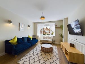 a living room with a blue couch and a tv at Stones Throw - stunning house, mins from beach and dogs welcome in Broadstairs