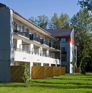 un gran edificio de apartamentos con una valla delante en Adonis Divonne-Les-Bains Résidence Du Lac, en Divonne-les-Bains